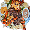 Parrillada platter with steak, chicken, shrimp skewers, quesadillas, vegetables, and sides.